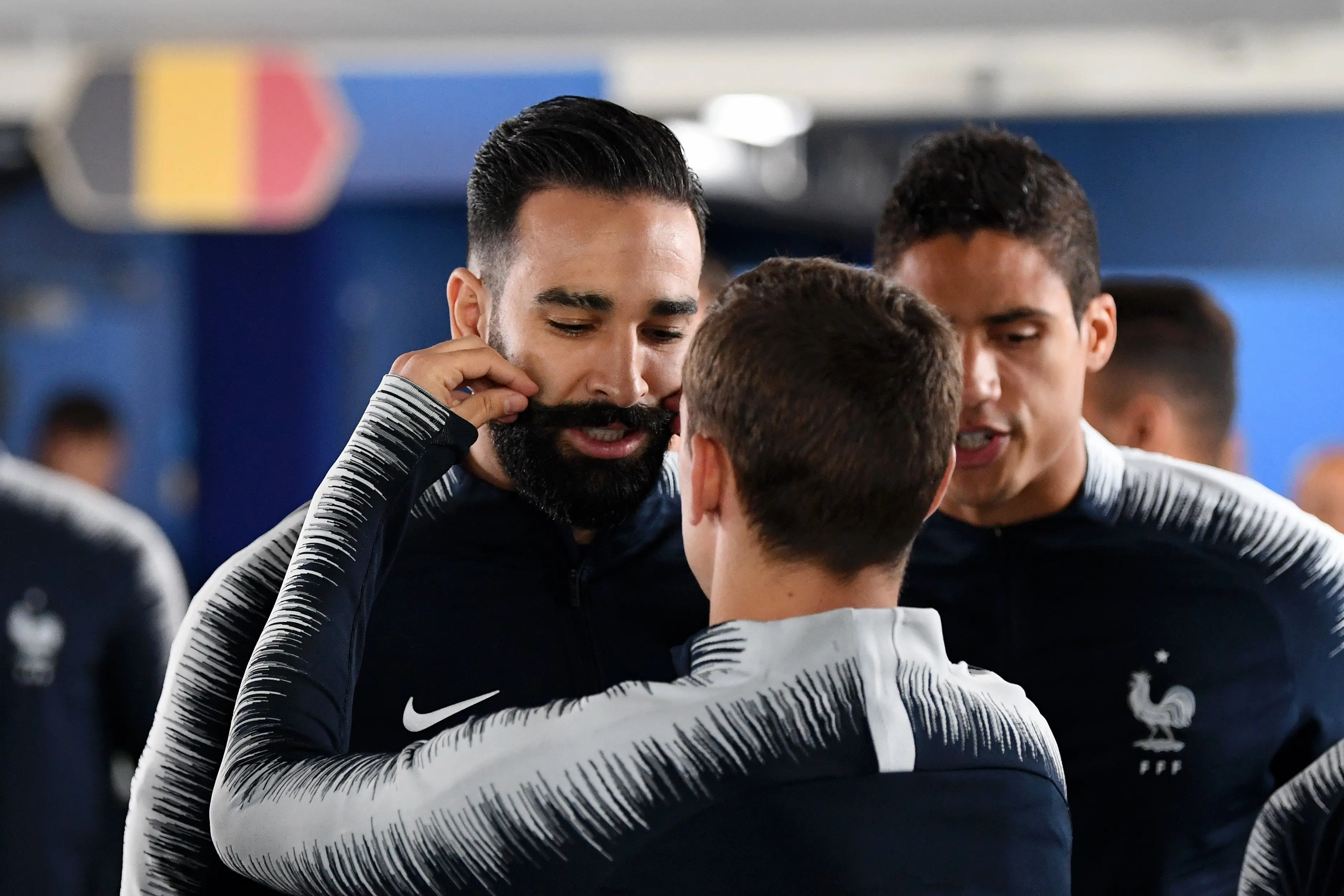 Antoine Griezmann toca el bigote de Adil Rami